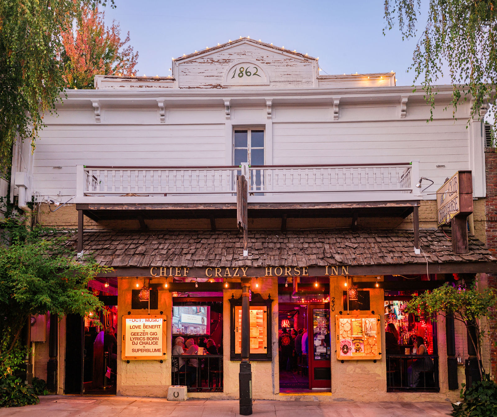 The lit 1862 façade of the Chief Crazy Horse Inn on Commercial Street at dusk